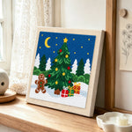 Gingerbread man and christmas tree punch needle artwork displayed on a table