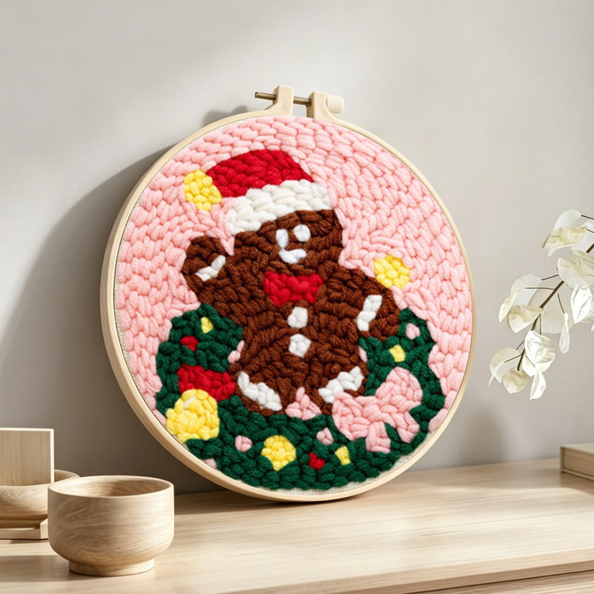Gingerbread man in wreath punch needle artwork displayed on a table