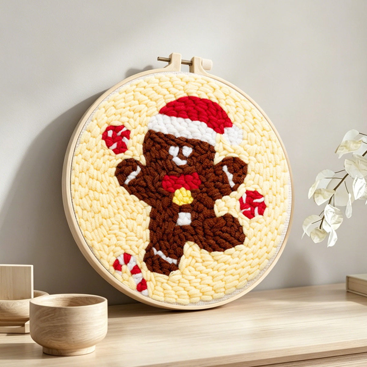 Gingerbread man with santa hat punch needle artwork displayed on a table
