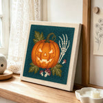 Glowing jack o lantern punch needle artwork displayed on a table