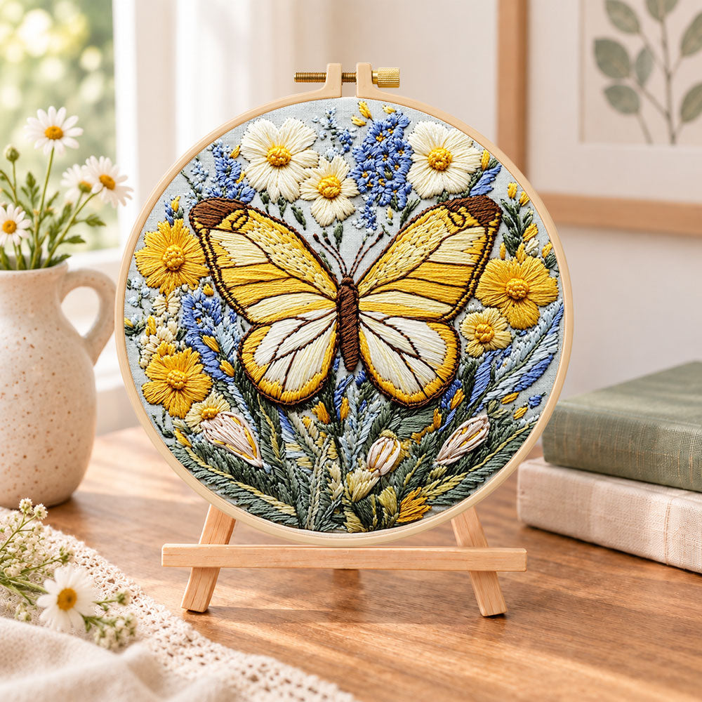 Golden butterfly with daisies embroidery kit finished hoop displayed on a wooden stand as cozy tabletop decor