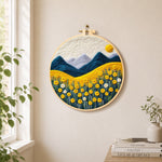 Golden flower field and snowy peaks needle felt wall art displayed in a bright home interior