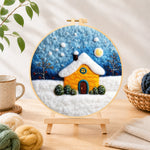 Finished golden snowy house under starry sky needle felting displayed on a wooden easel