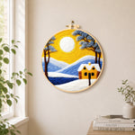 Golden sun and blue mountain snowscape needle felt wall art displayed in a bright home interior