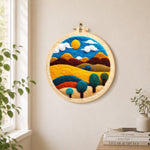 Golden sun and swirling tree hills needle felt wall art displayed in a bright home interior