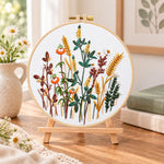 Golden wheat and poppy blooms embroidery kit finished hoop displayed on a wooden stand as cozy tabletop decor