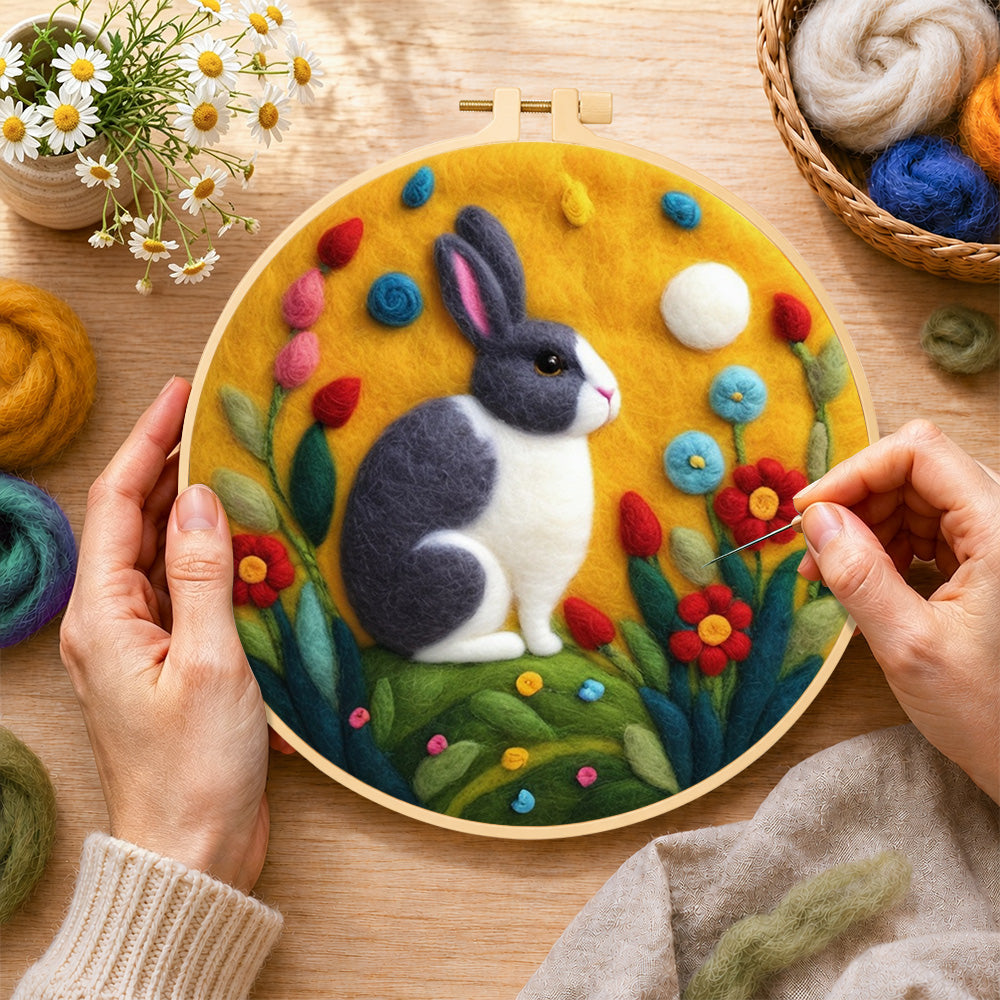 Creating the gray and white rabbit among flowers wool painting by hand with a felting needle