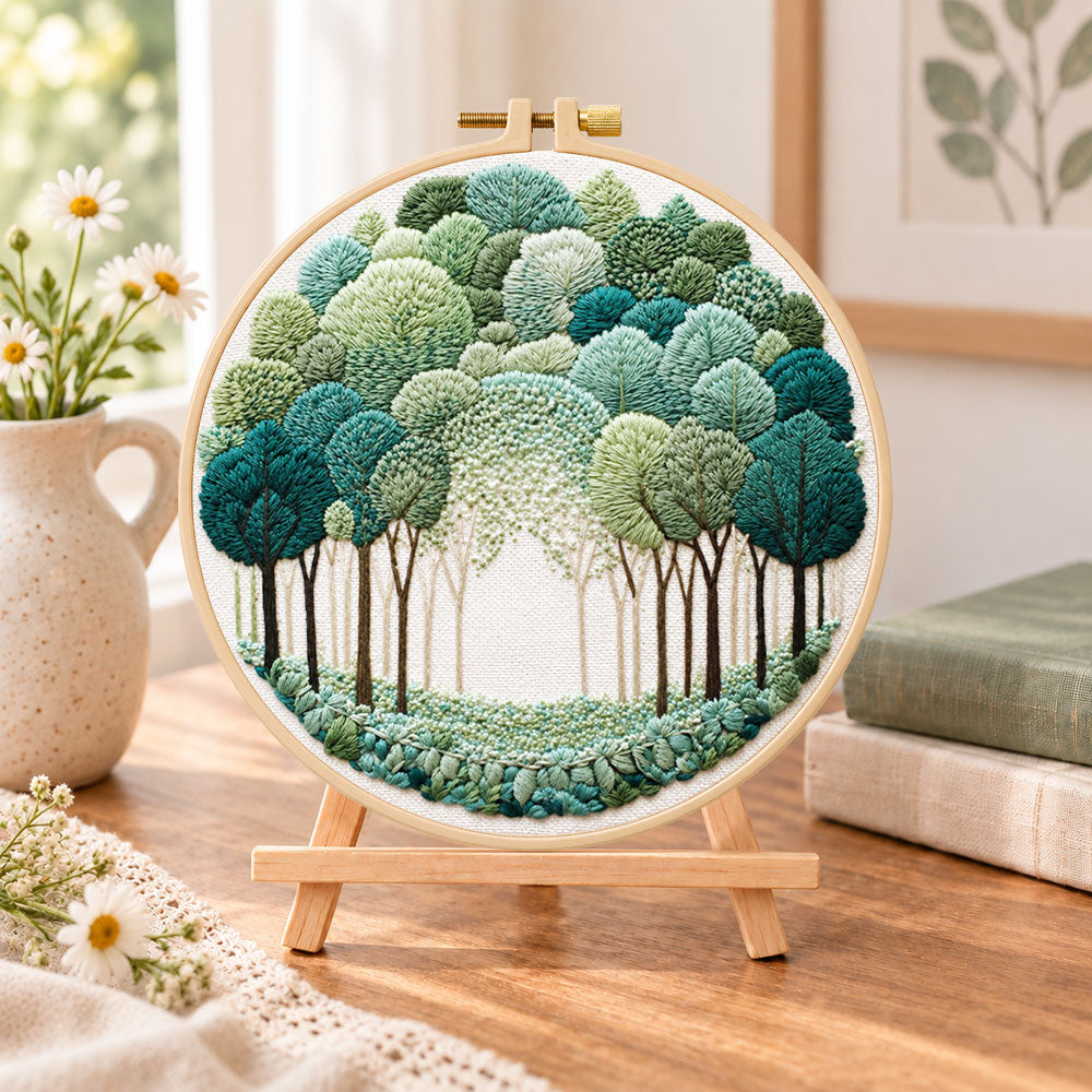Green forest path embroidery kit finished hoop displayed on a wooden stand as cozy tabletop decor