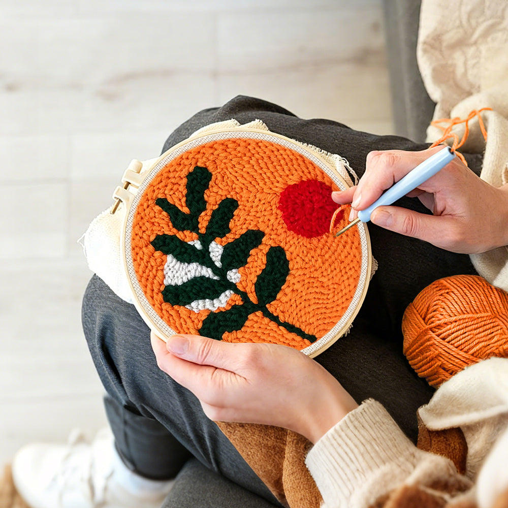 Creating handmade green leaves and red sun punch needle artwork