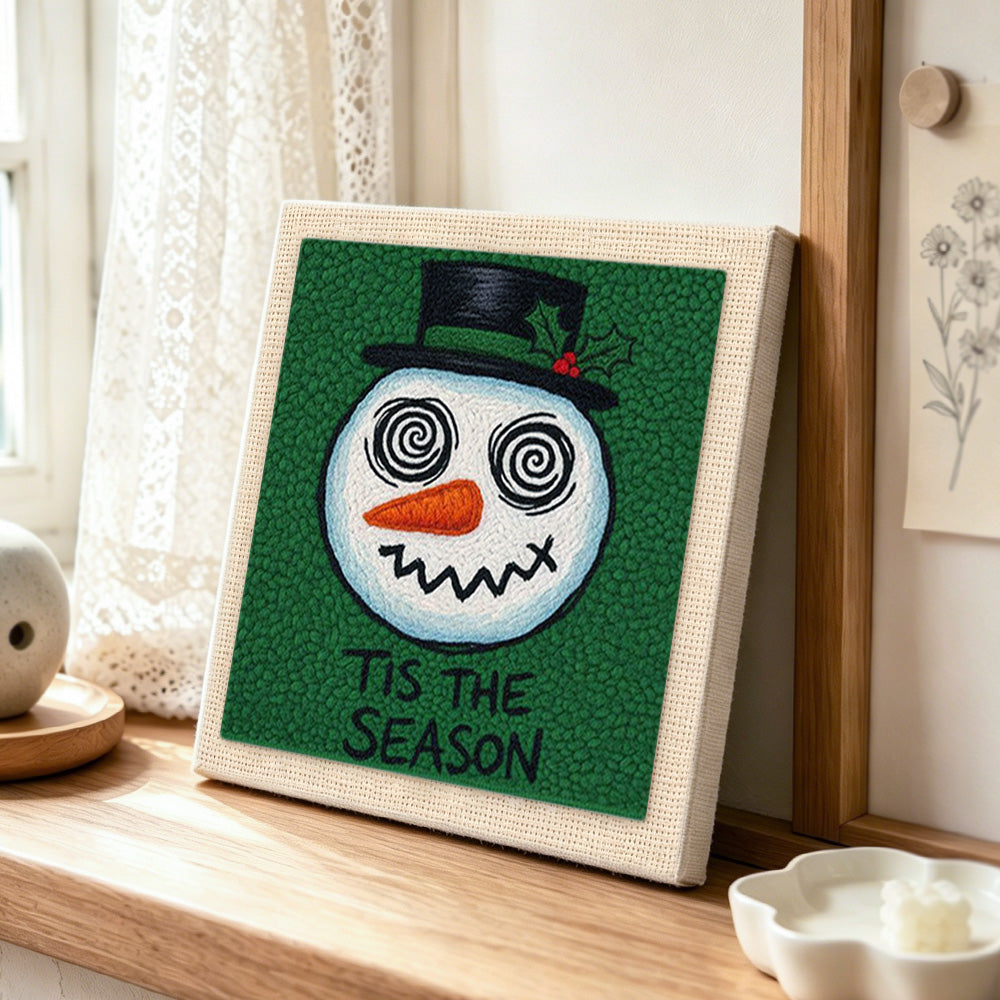 Grinning spiral eye snowman punch needle artwork displayed on a table