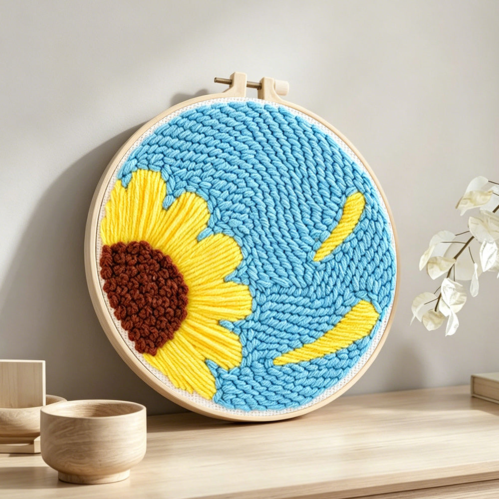 Half sunflower on blue background punch needle artwork displayed on a table