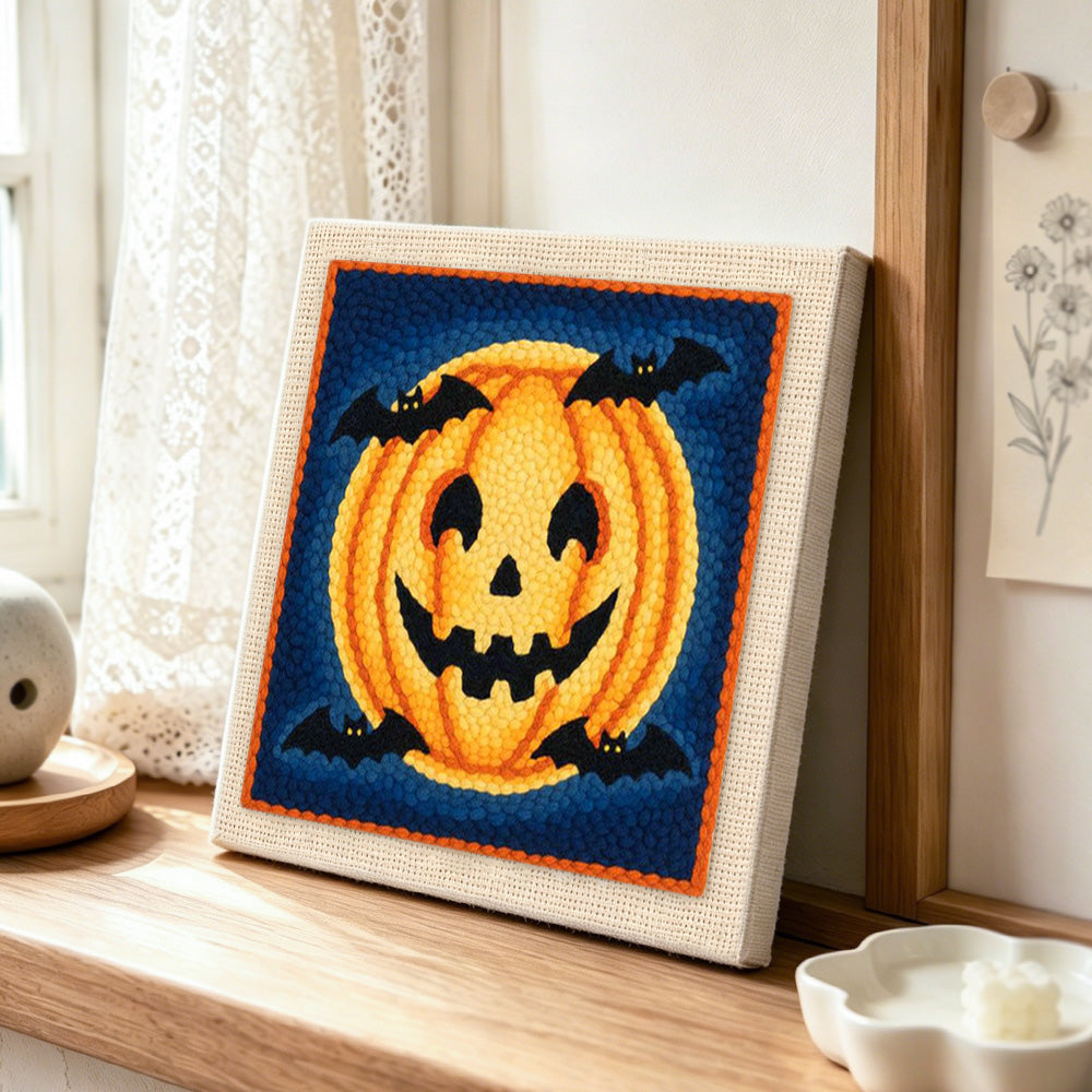 Halloween pumpkin and bats punch needle artwork displayed on a table