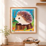 Finished hedgehog on tree stump cross stitch artwork displayed as home decor