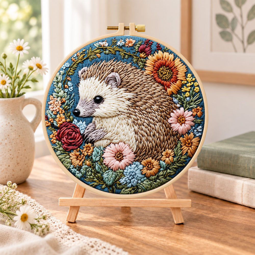 Hedgehog with sunflower blooms embroidery kit finished hoop displayed on a wooden stand as cozy tabletop decor