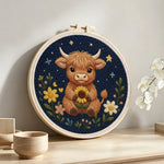 Highland cow and flowers at night punch needle artwork displayed on a table