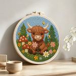 Highland cow and mushrooms in spring punch needle artwork displayed on a table