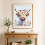 Finished highland cow with purple wildflowers cross stitch artwork displayed as home decor