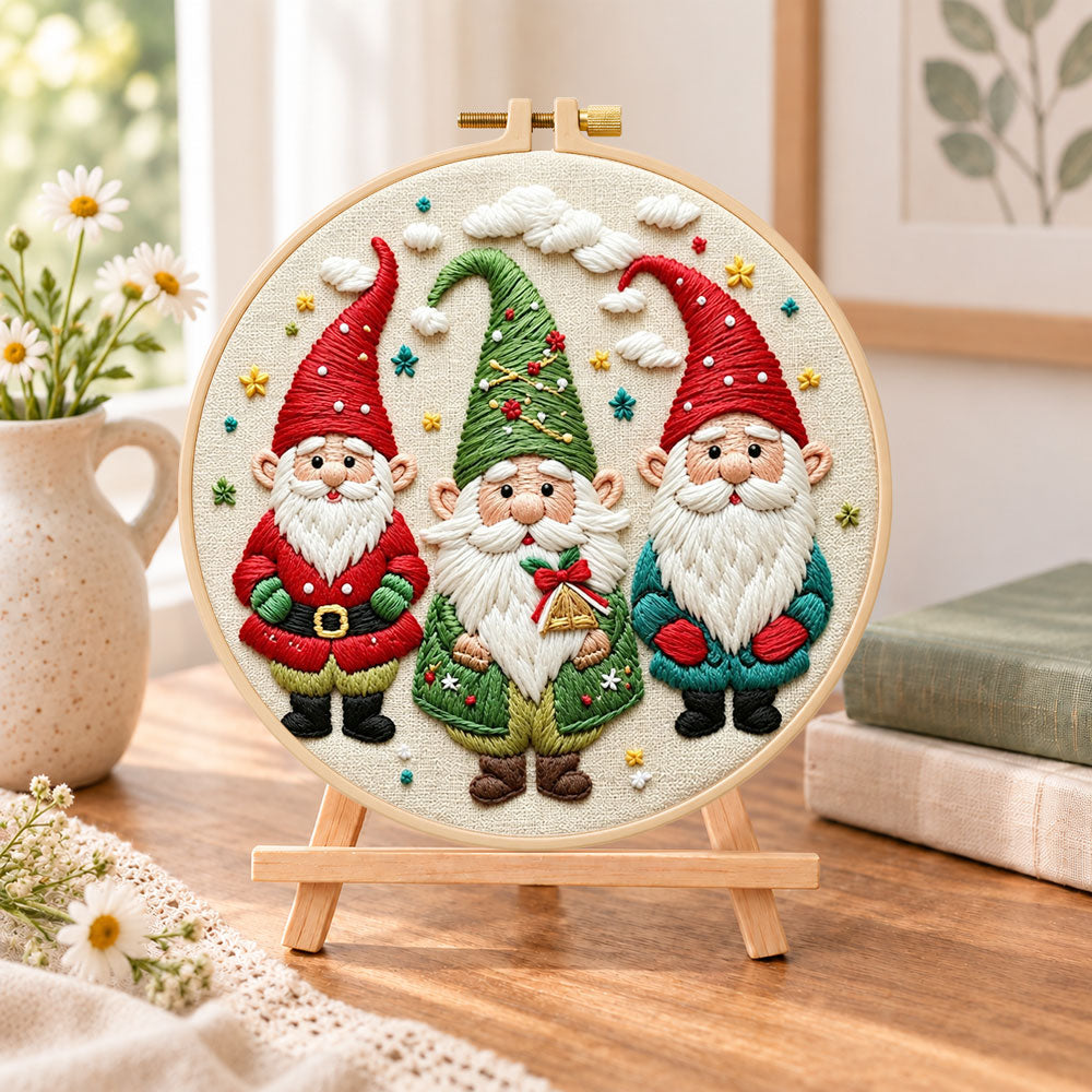 Holiday gnome trio embroidery kit finished hoop displayed on a wooden stand as cozy tabletop decor