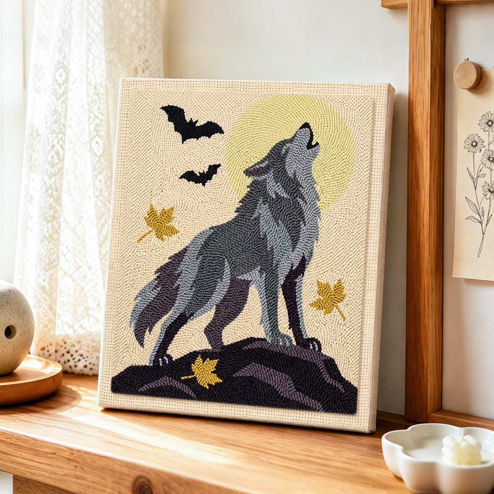 Howling wolf under full moon punch needle artwork displayed on a table