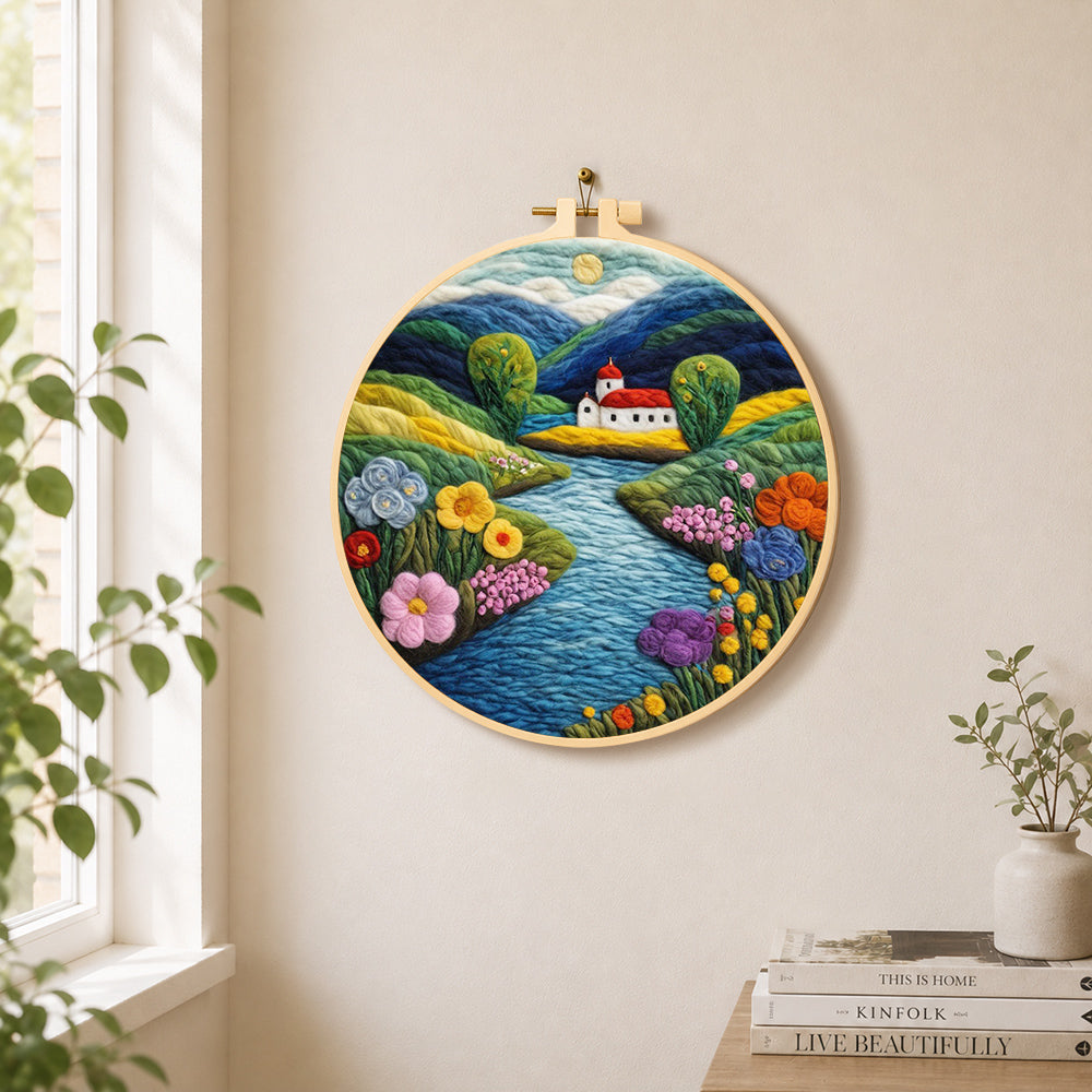 Idyllic mountain village and river needle felt wall art displayed in a bright home interior