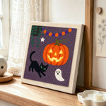 Jack o lantern and cat punch needle artwork displayed on a table