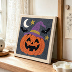 Jack o lantern wearing witch hat punch needle artwork displayed on a table