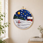 Jolly snowman and red winter cottage needle felt wall art displayed in a bright home interior