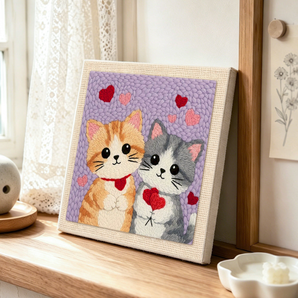 Kittens holding hearts punch needle artwork displayed on a table