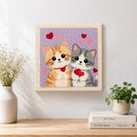 Finished kittens holding hearts artwork displayed on a wall