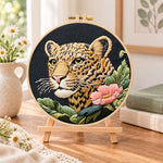 Leopard and pink wildflower embroidery kit finished hoop displayed on a wooden stand as cozy tabletop decor