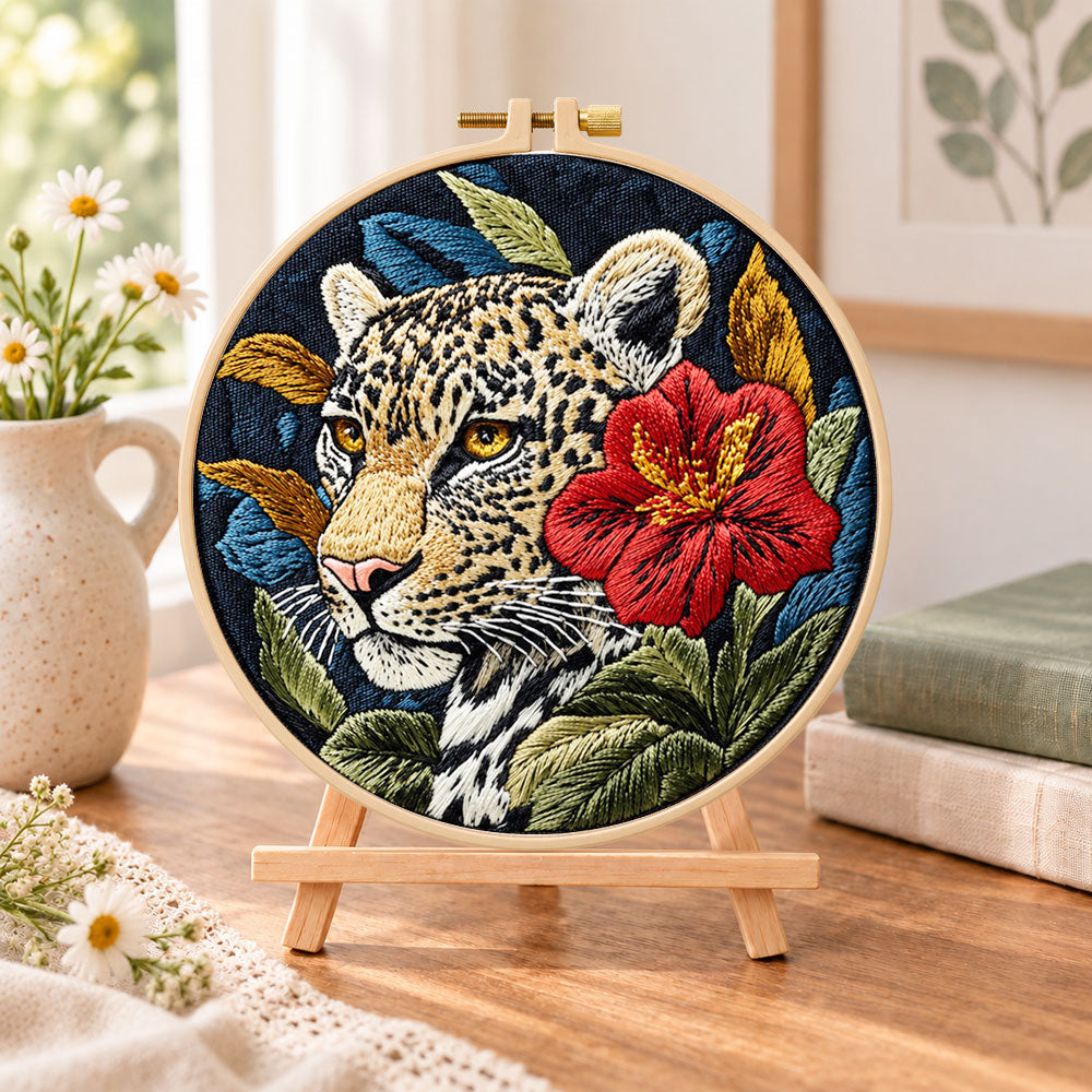 Leopard with red hibiscus embroidery kit finished hoop displayed on a wooden stand as cozy tabletop decor