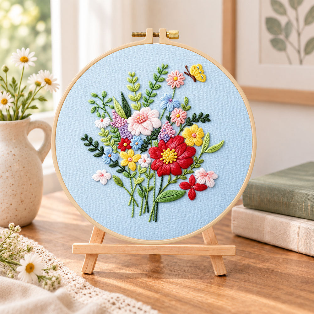 Light blue florals with butterfly embroidery kit finished hoop displayed on a wooden stand as cozy tabletop decor