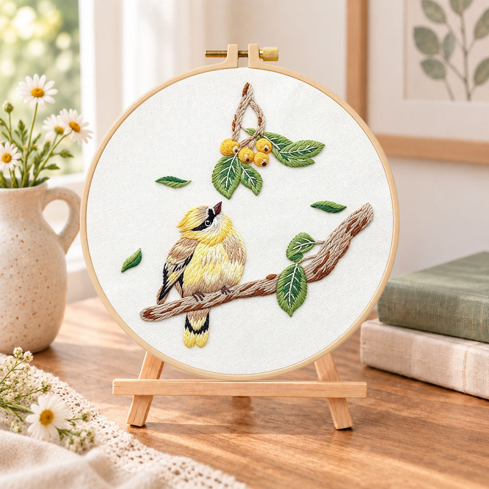 Little bird looking at loquat fruits embroidery kit finished hoop displayed on a wooden stand as cozy tabletop decor