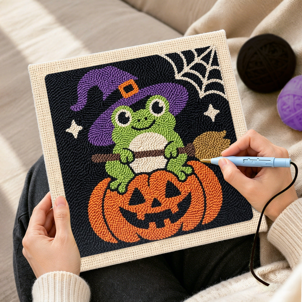Creating handmade little witch frog sitting on pumpkin punch needle artwork