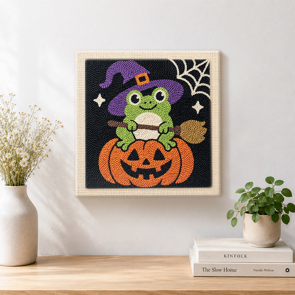 Finished little witch frog sitting on pumpkin artwork displayed on a wall