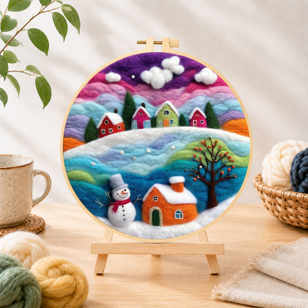 Finished magical rainbow snowy village at christmas needle felting displayed on a wooden easel
