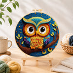 Finished majestic rainbow owl on a branch needle felting displayed on a wooden easel