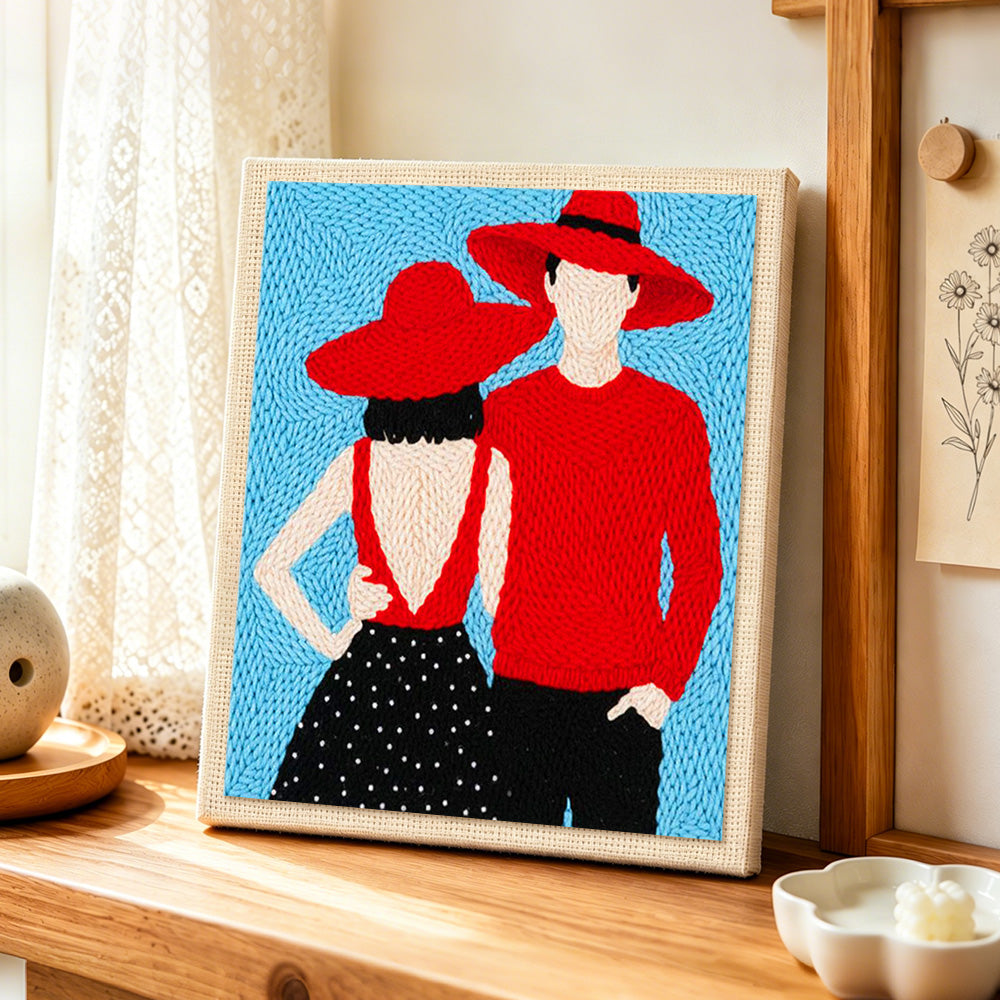 Matching red hats couple punch needle artwork displayed on a table
