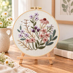 Mauve pastel blossoms embroidery kit finished hoop displayed on a wooden stand as cozy tabletop decor