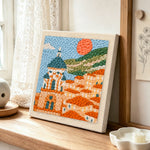 Mediterranean coastal town punch needle artwork displayed on a table