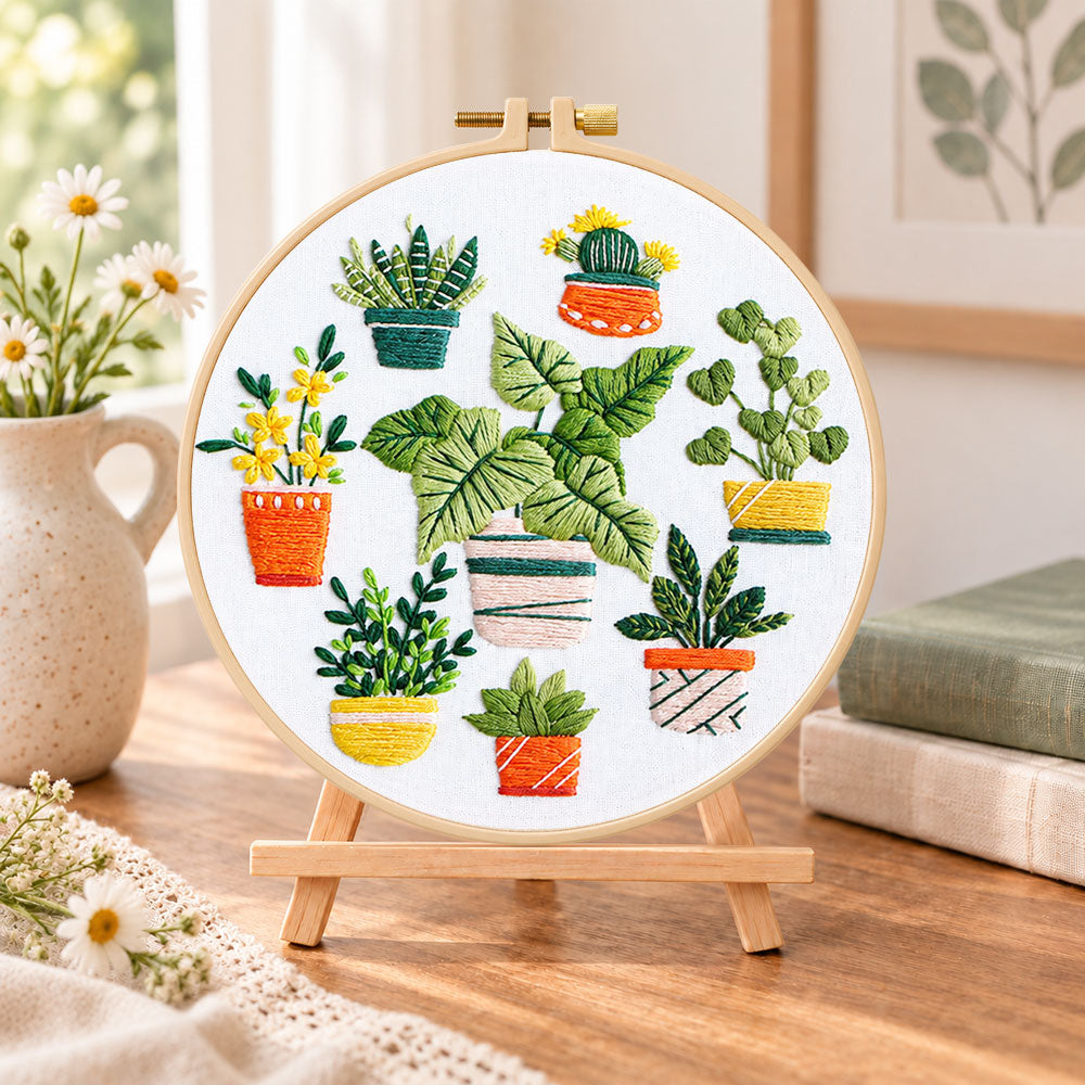 Mixed mini potted greenery embroidery kit finished hoop displayed on a wooden stand as cozy tabletop decor
