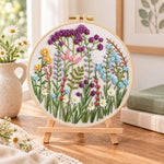 Mixed wildflower field embroidery kit finished hoop displayed on a wooden stand as cozy tabletop decor