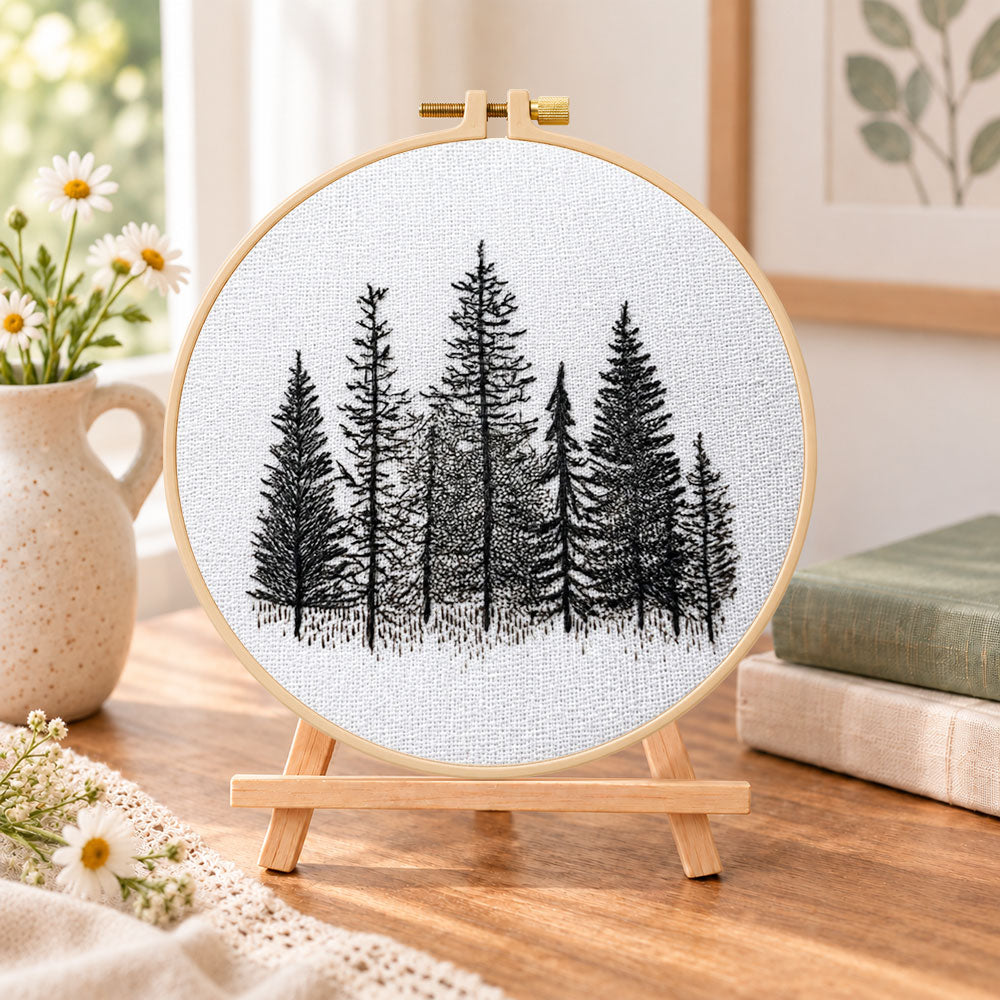 Monochrome pine woods embroidery kit finished hoop displayed on a wooden stand as cozy tabletop decor