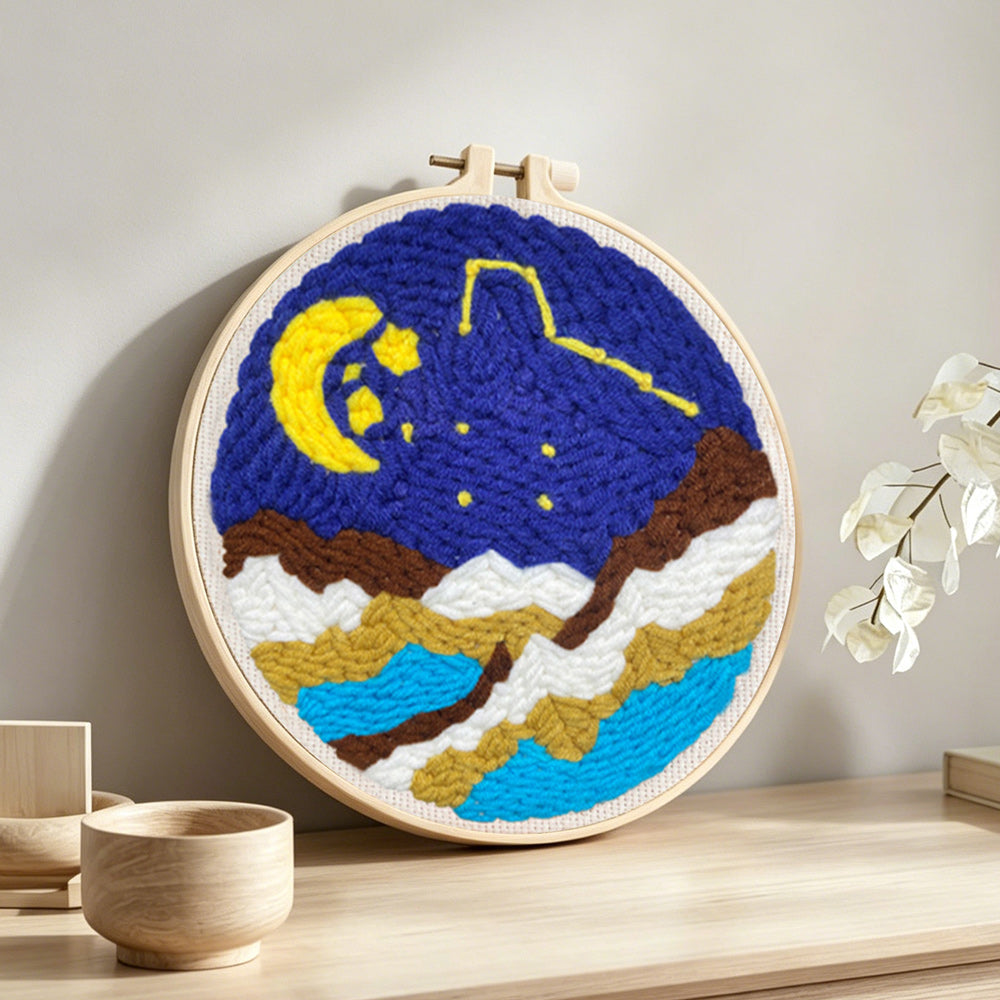 Moon and starry night over mountains punch needle artwork displayed on a table