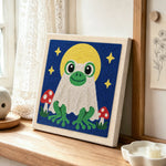Moonlit frog ghost punch needle artwork displayed on a table