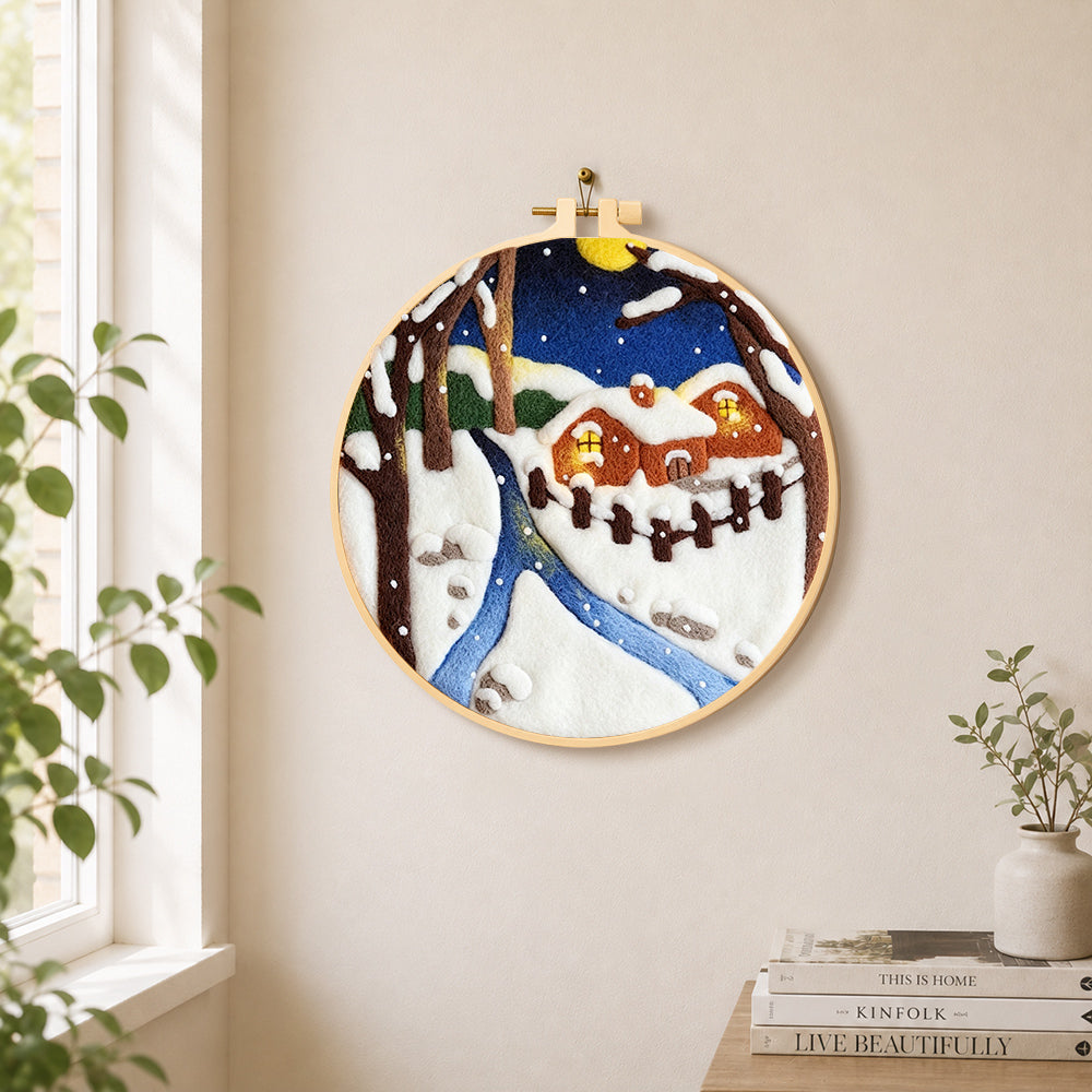 Moonlit snowy cabin with warm glow needle felt wall art displayed in a bright home interior