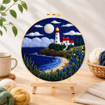 Finished moonlit white lighthouse and blue roses needle felting displayed on a wooden easel