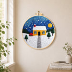 Moonlit yellow house and red bushes needle felt wall art displayed in a bright home interior