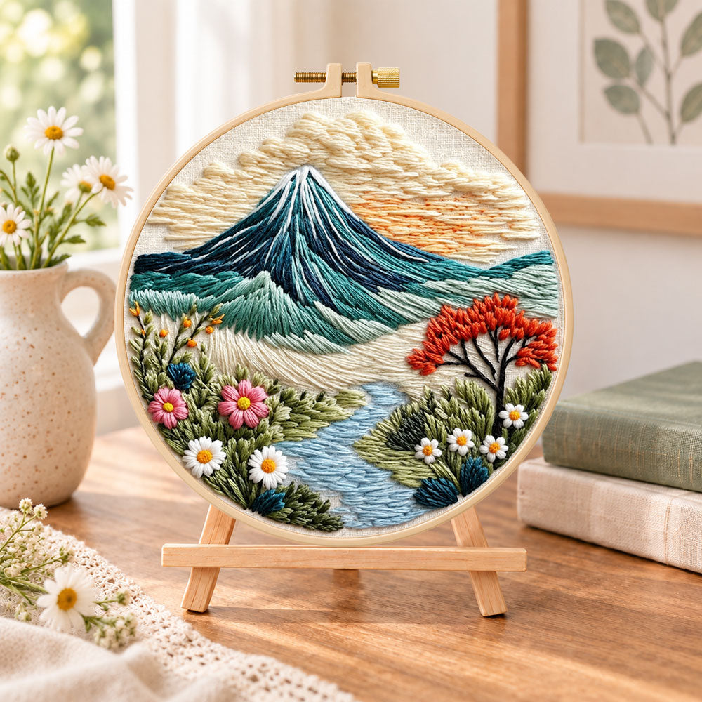 Mountain riverside landscape embroidery kit finished hoop displayed on a wooden stand as cozy tabletop decor