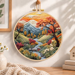 Mountain stream at sunset embroidery hoop wall art displayed as warm and cozy handmade home decor